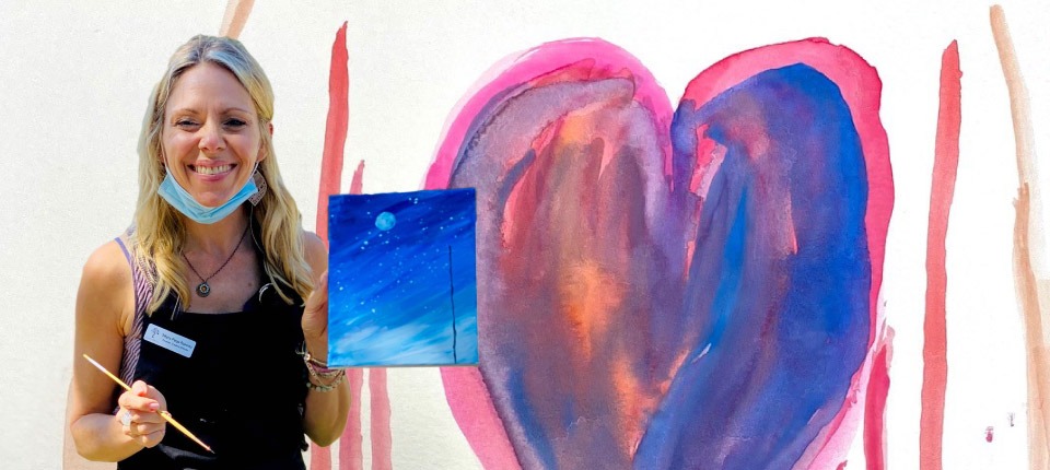 Tiffany Ramirez holding a painting and smiling