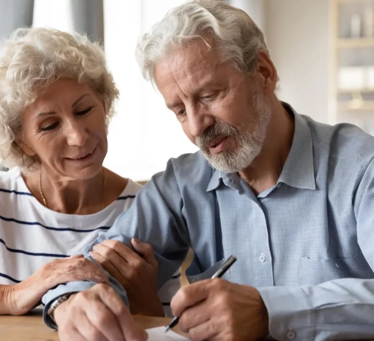 Older woman and man sitting at table filling out paperwork