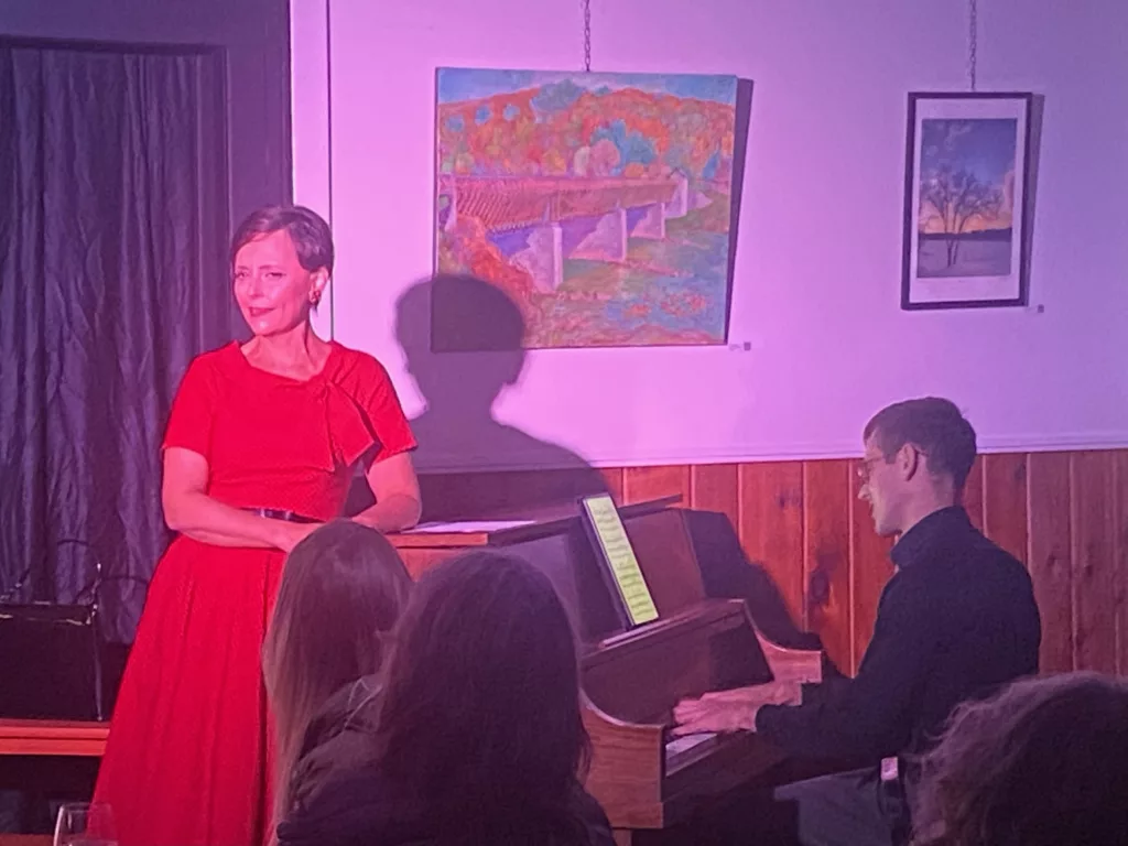 Brooke Schooley wearing a red dress performing Who Knows Where or When next to a man playing a piano.