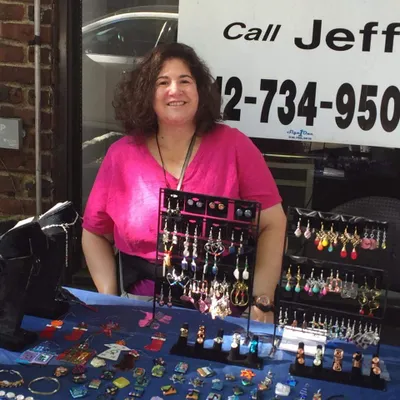Naomi Rabinowitz standing behind a handmade jewelry counter