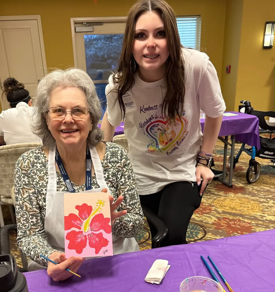 Roselyn with resident holding a painting of a flower