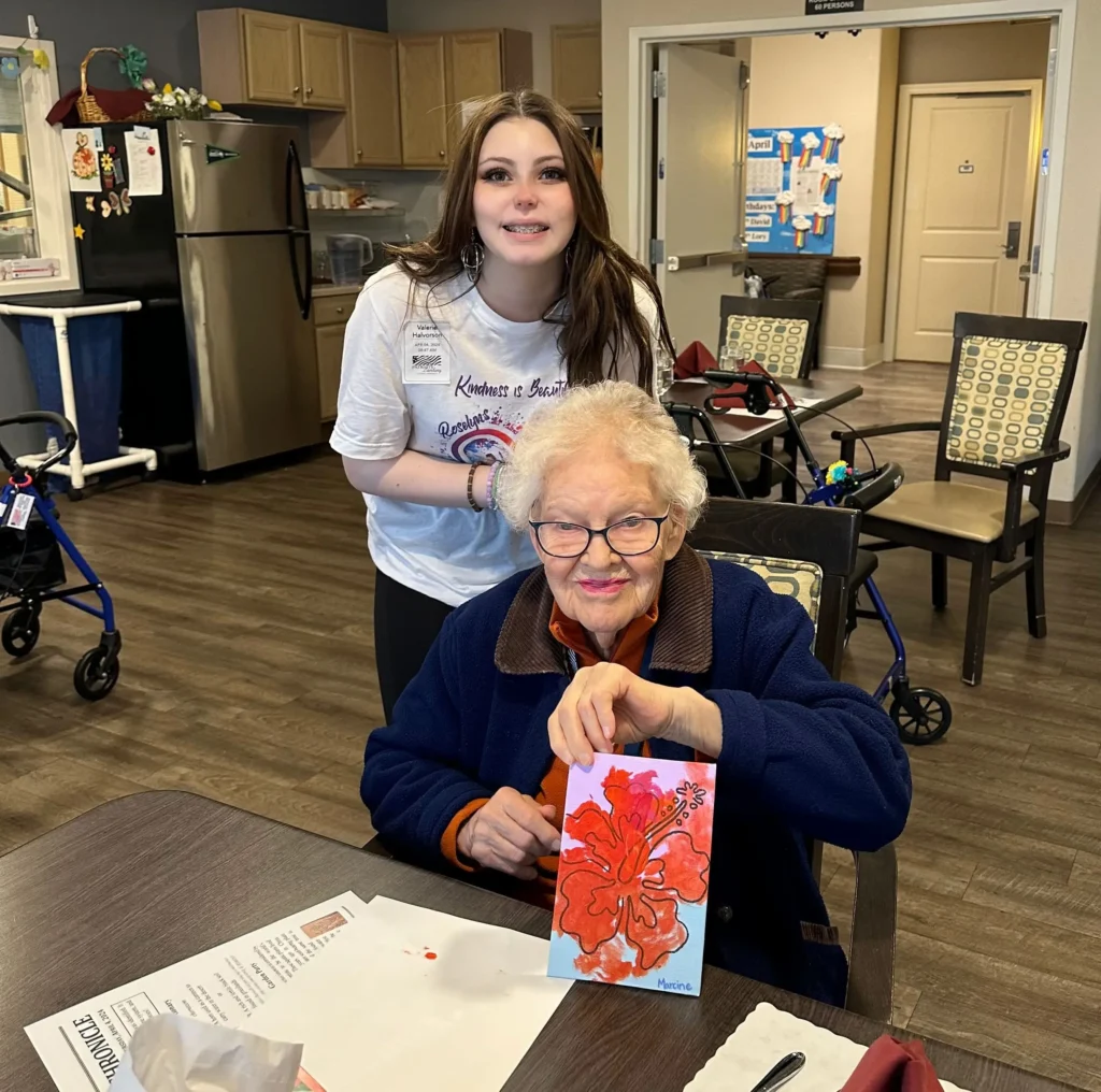 Roselyn with resident holding a painting of a flower