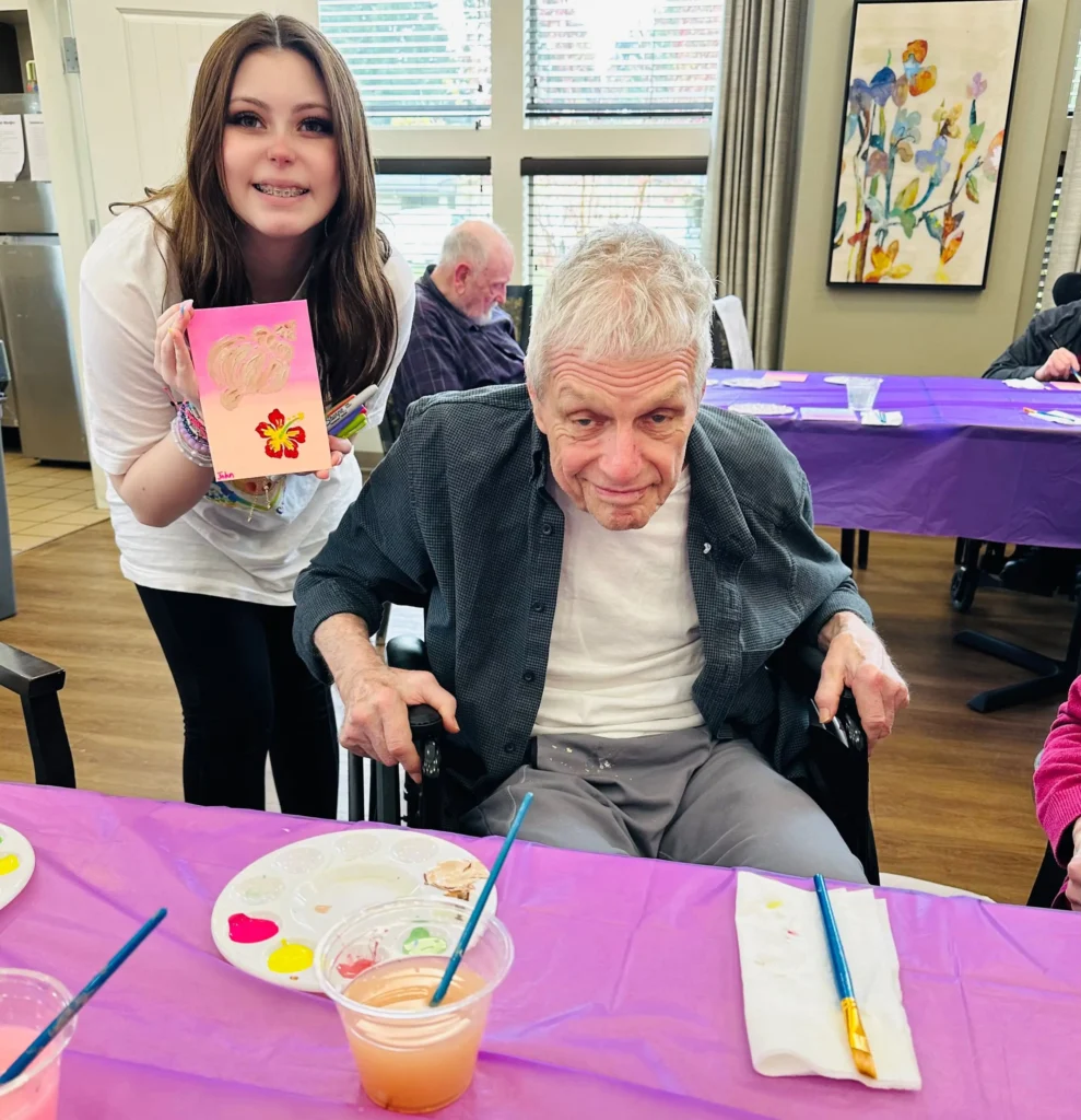 Roselyn with resident holding a painting of a flower