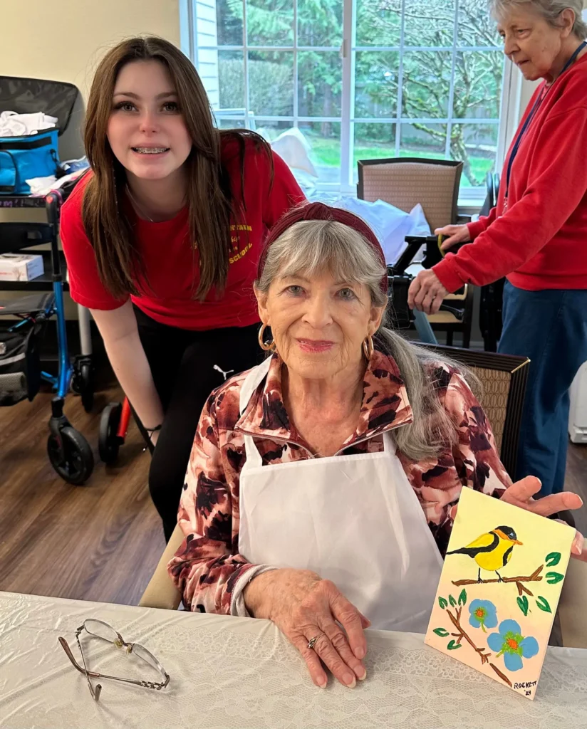 Roselyn with resident holding a painting of a bird