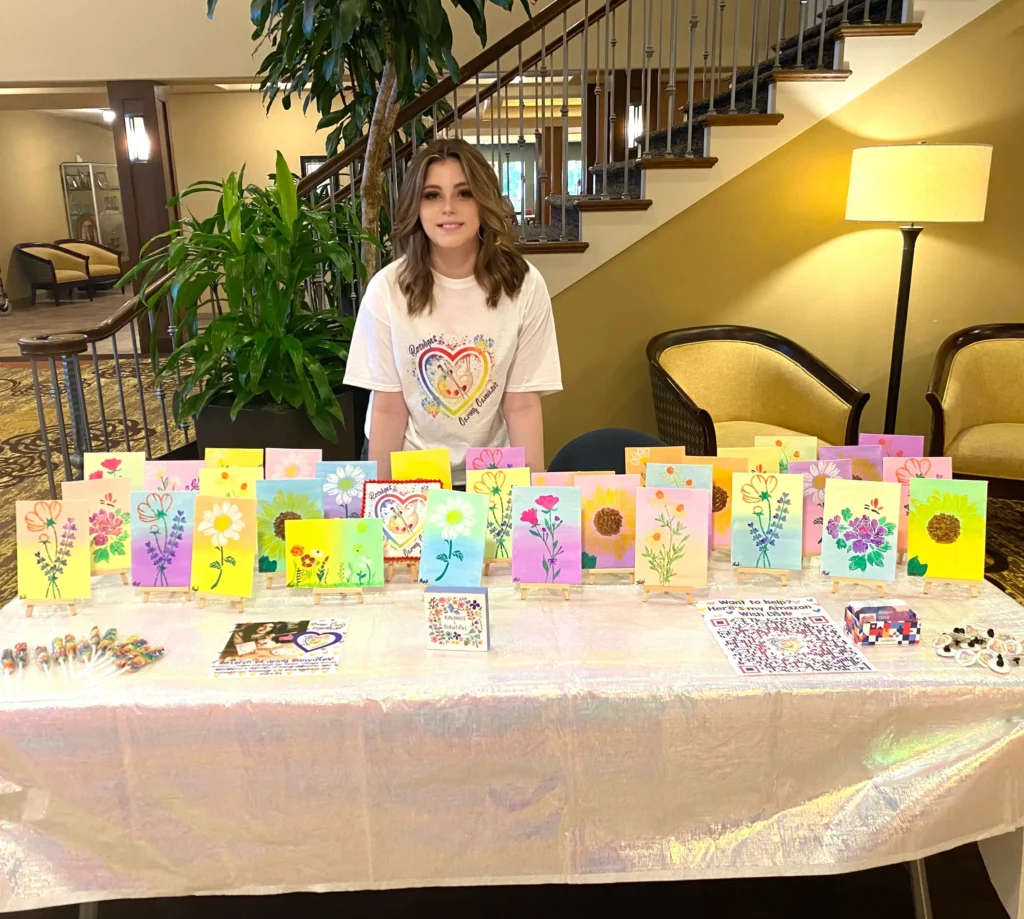 Roselyn behind table of multiple finished canvases