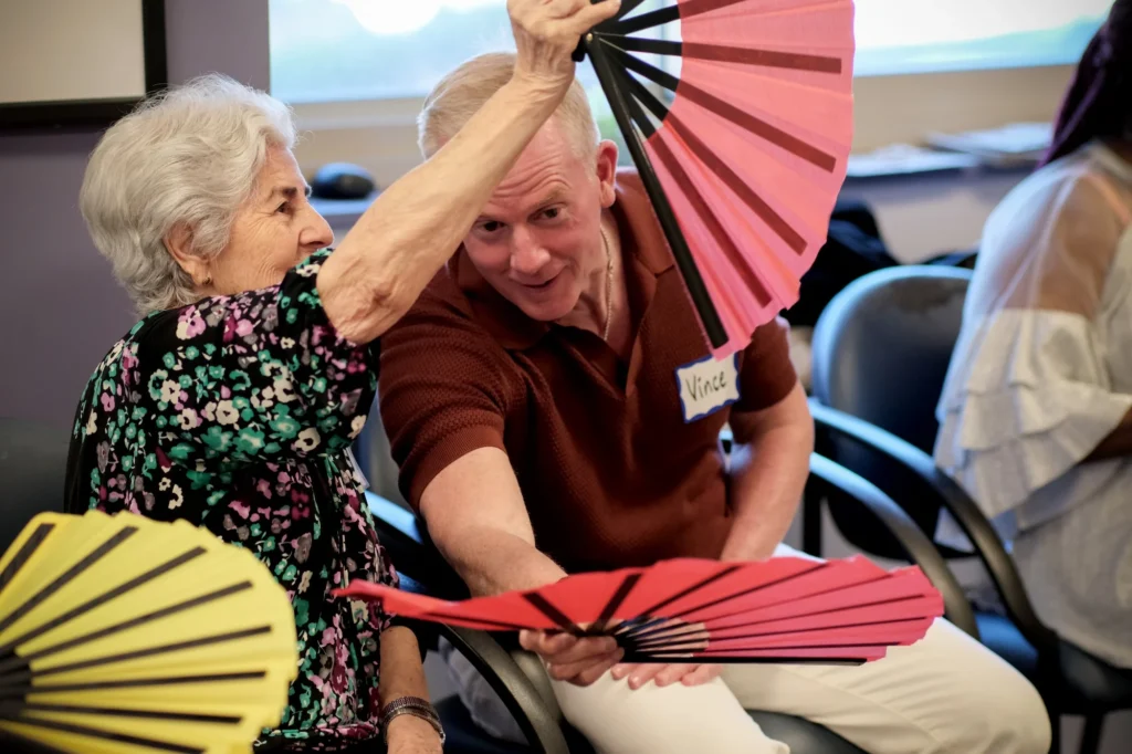 Man and woman with hand fans smiling