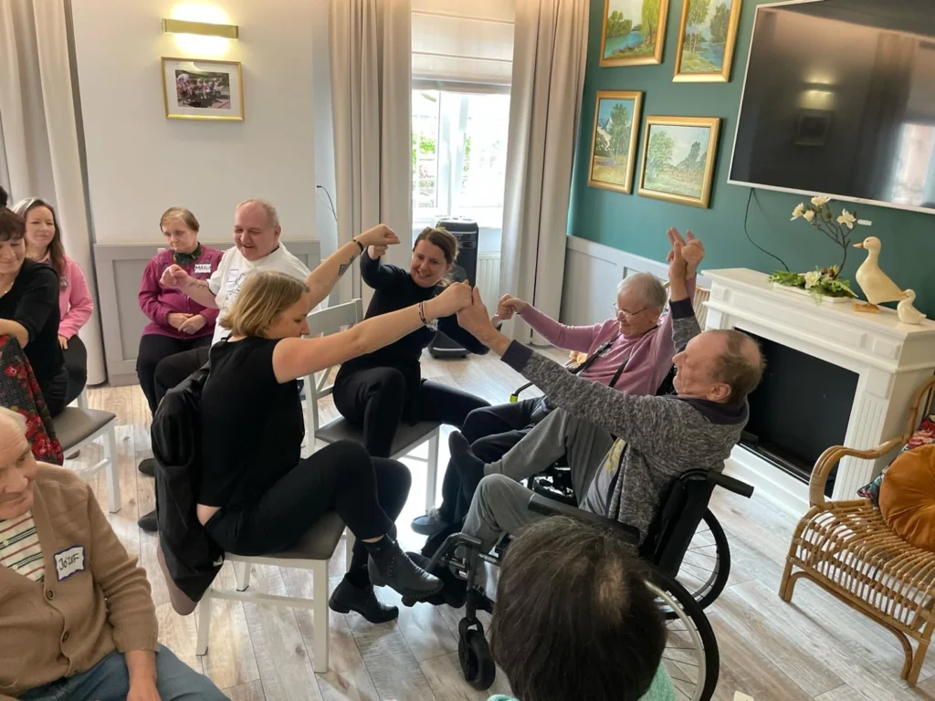 Group seated with hands raised and together dancing to music
