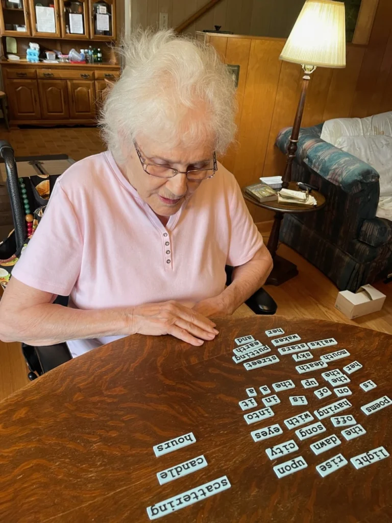 Woman sits at a living room table, engaging with blocks of text to create something new