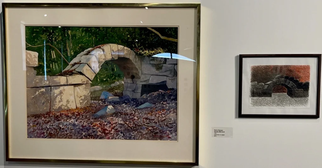 Two images hang in a gallery, both of the same subject: a stone-worked arc. They are artistically depicted with different styles. 