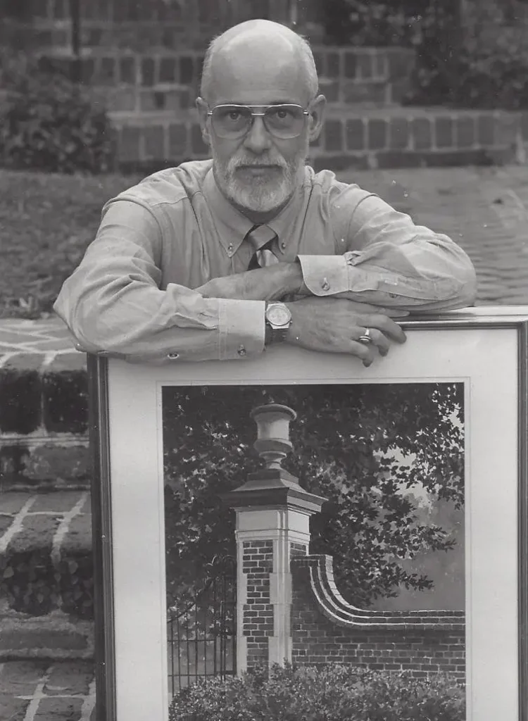 A man leans on a framed images of a light post. The photo is black and white.