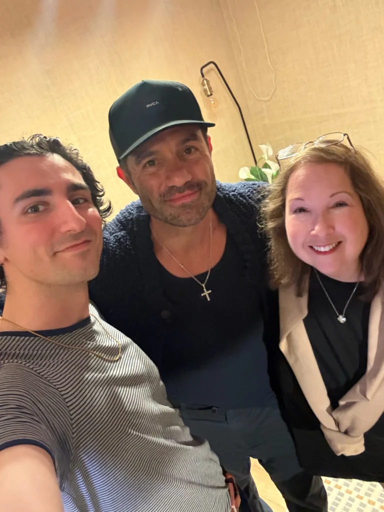 Three people smile at a camera, two men and one woman. 