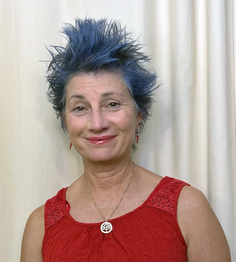 Headshot of Tiffany Riley in a red shirt and blue hair.