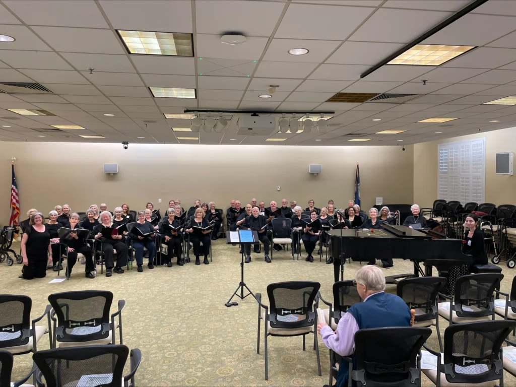 A room is filled with elderly people singing in an assembly