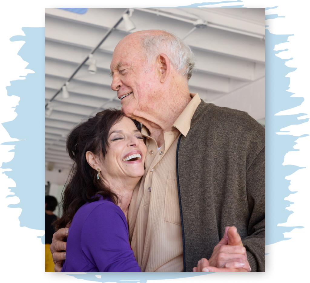 A woman dances with her father, both smiling and laughing