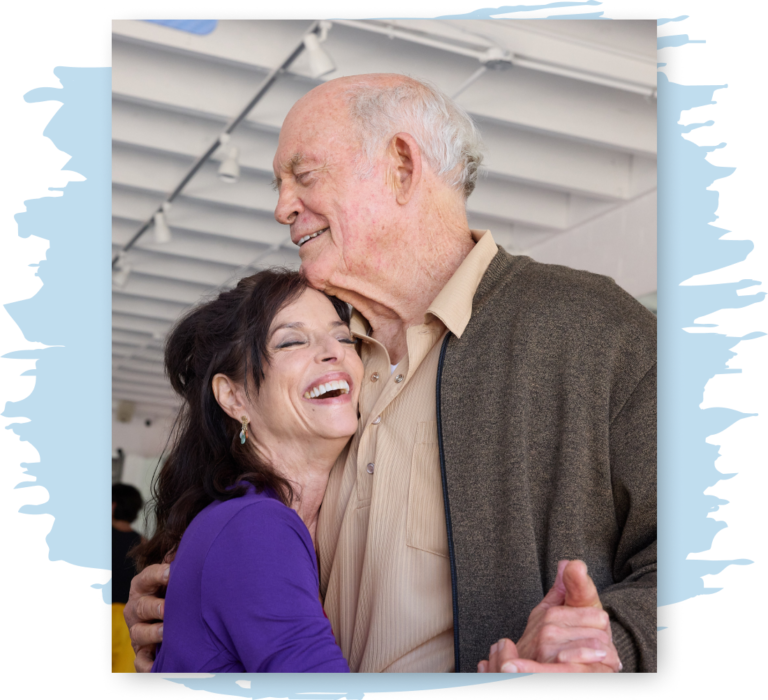 A woman dances with her father, both smiling and laughing