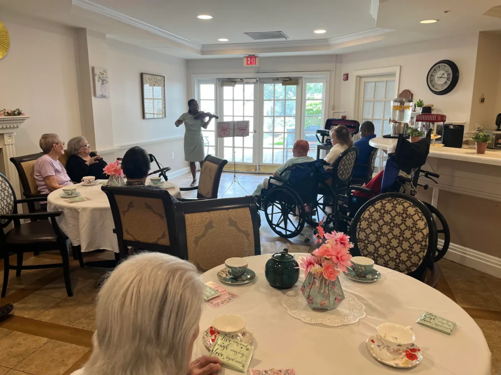 Melanie plays the violin in a senior center before a crowd of seniors