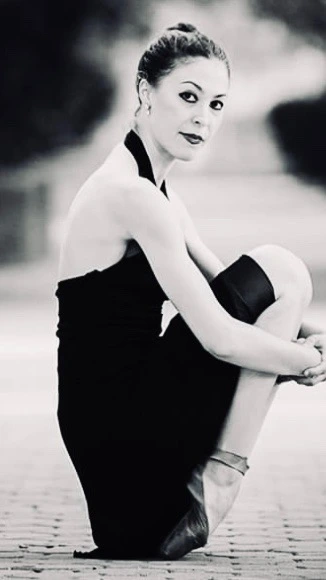 Emily dressed in her dance attire, with hair pulled back into bun looking into the camera. 