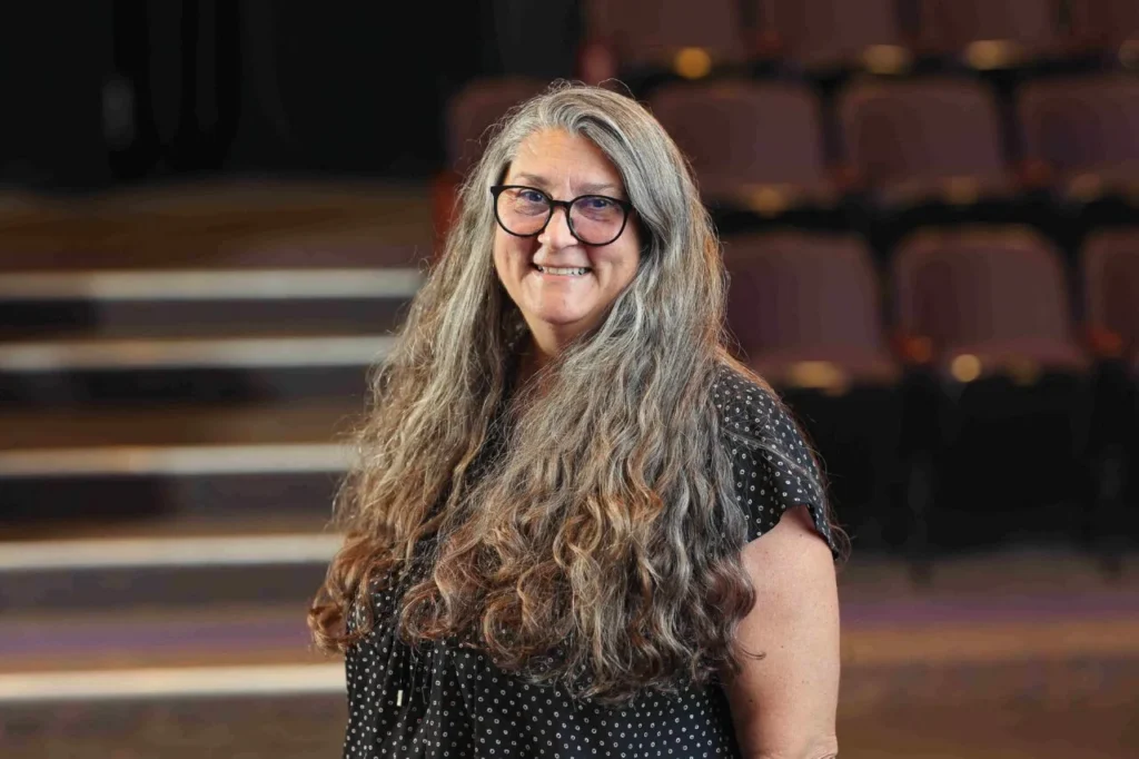 margeret smiles at the camera, with long gray hair, and glasses