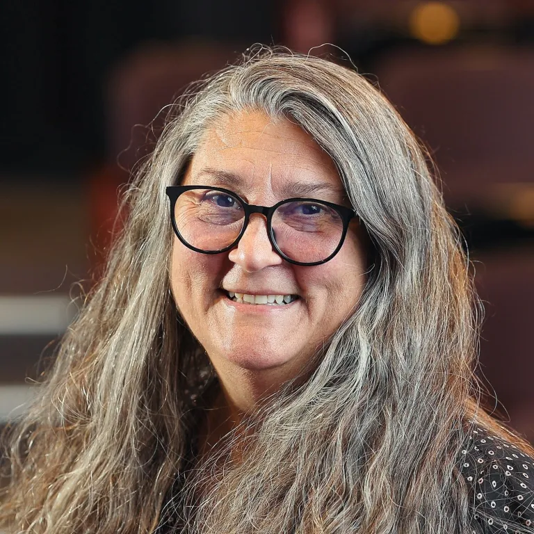 margeret smiles at the camera, with long gray hair, and glasses