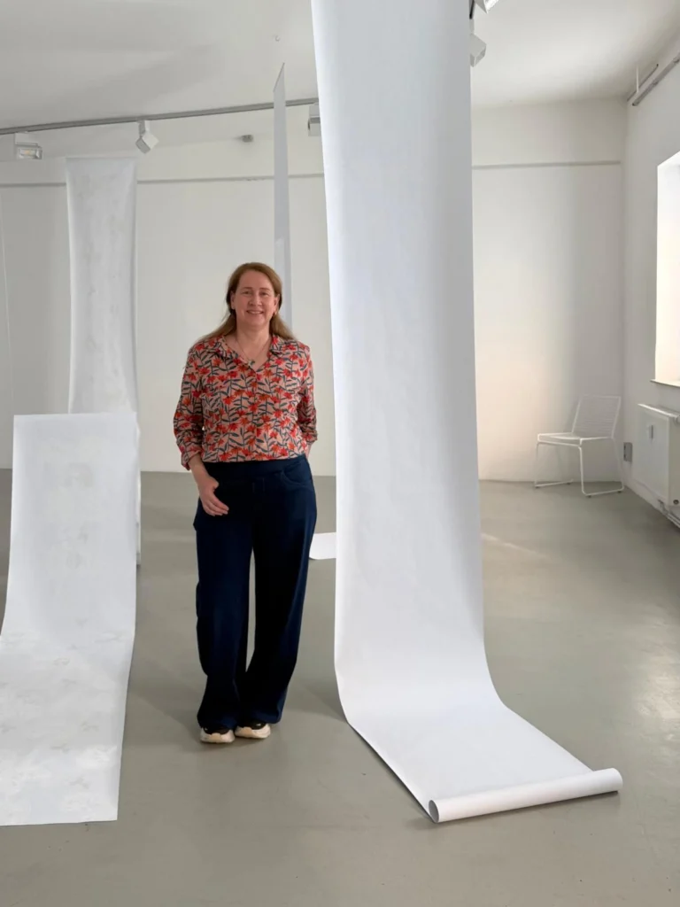 Michelle stands next to very large brain scan scrolls hanging from the ceiling.