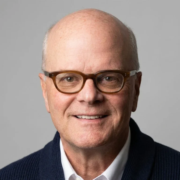 robert singer smiling at the camera, with dark brown glasses and a navy suit